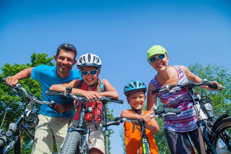 Fahrradtour mit Kind - Junge Familie mit 2 Kindern beim Radausflug schaut fröhlich in die Kamera