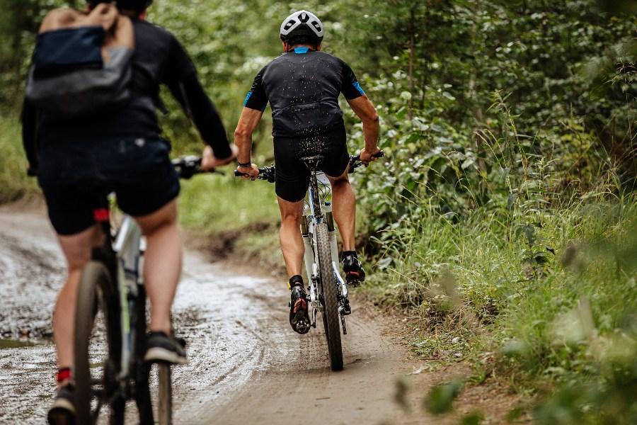 Zwei junge Leute radeln durch den Wald - Po-Schmerzen nach dem Fahrradfahren