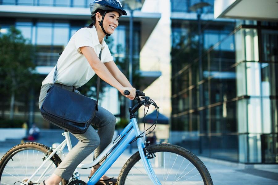 Junge Frau fährt auf dem Fahrrad zur Arbeit - Fahrrad statt Auto nehmen