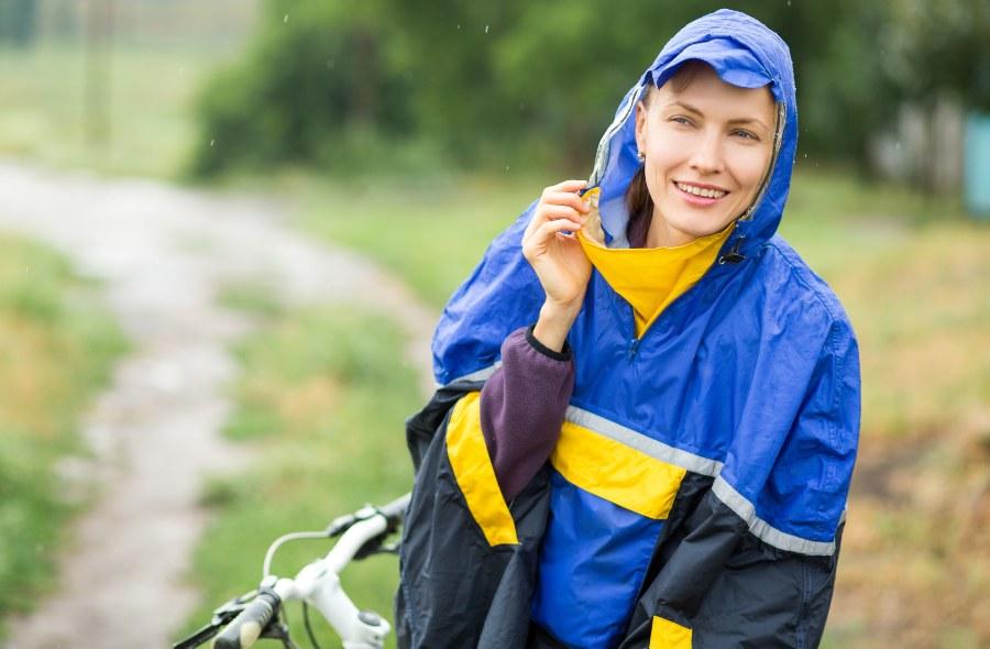 Junge Frau mit Fahrrad, mit Regenjacke, klassischer Art