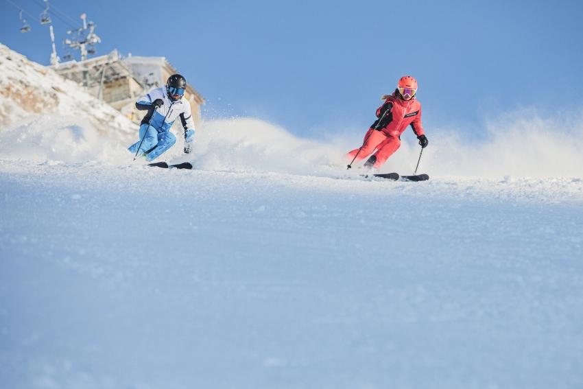 Das Material der Skibekleidung sollte wind- und wetterfest sowie wasserdicht sein Paar beim Skifahren in Skibekleidung