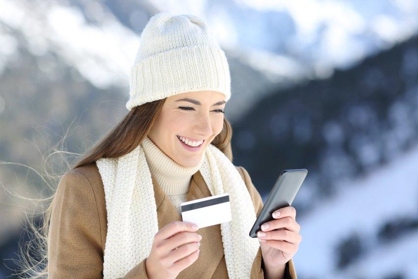 Junge Frau im Winter mit Handy und Kreditkarte