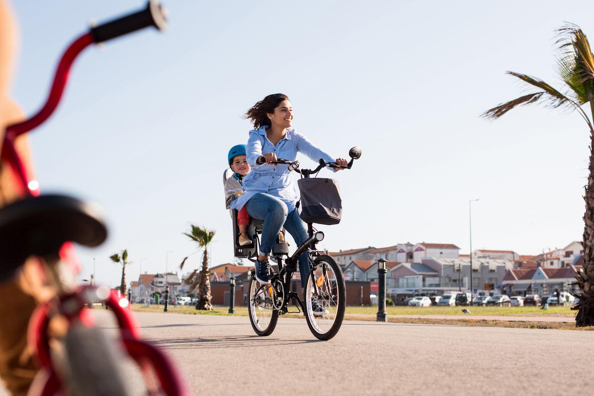 Junge Mutter fährt Fahrrad mit Kleinkind im Kindersitz